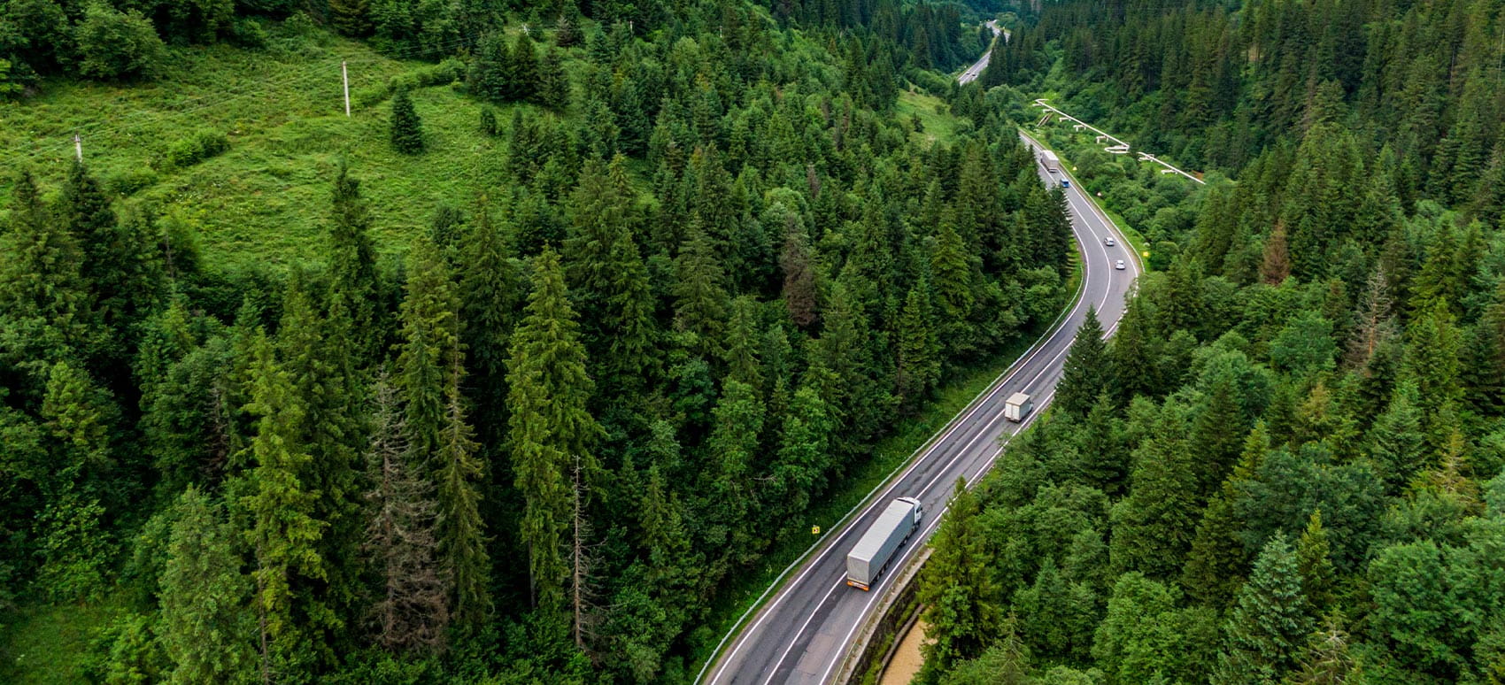 Aerial view of a landscape of a cargo truck on the highway driving on an asphalt road through the mountains.