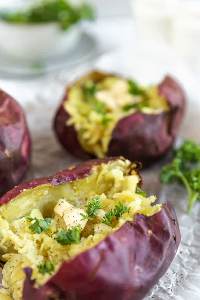 An overview shot of a baked sweet potato topped with butter and parsley