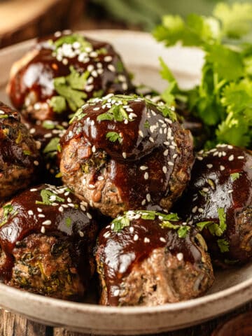 A bowl of baked asian meatballs with whole30 teriyaki sauce on a wood background