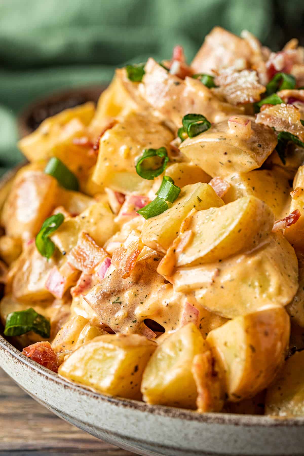 A close up view of a bowl of buffalo ranch potato salad on a wood background.