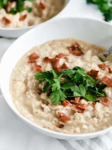 A bowl of cauliflower chowder topped with bacon and parsley