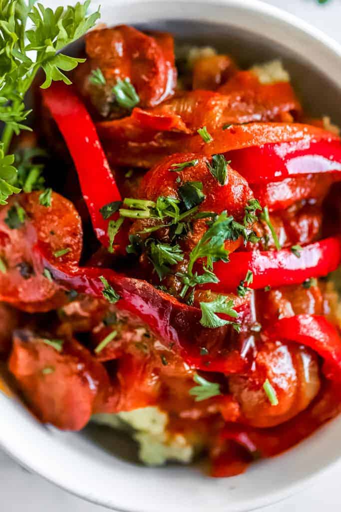 A close up of a bowl of thai coconut curry with peppers and onions 