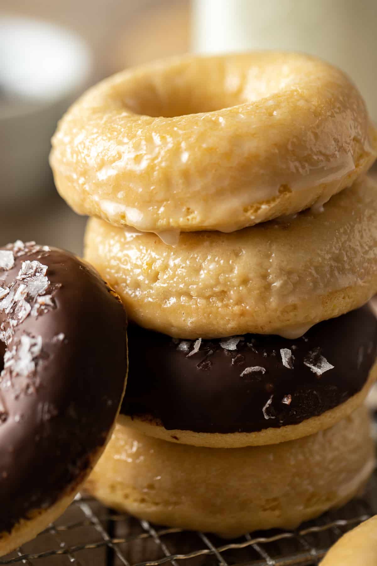 A stack of donuts half glazed and half chocolate on a wire cooling rack.