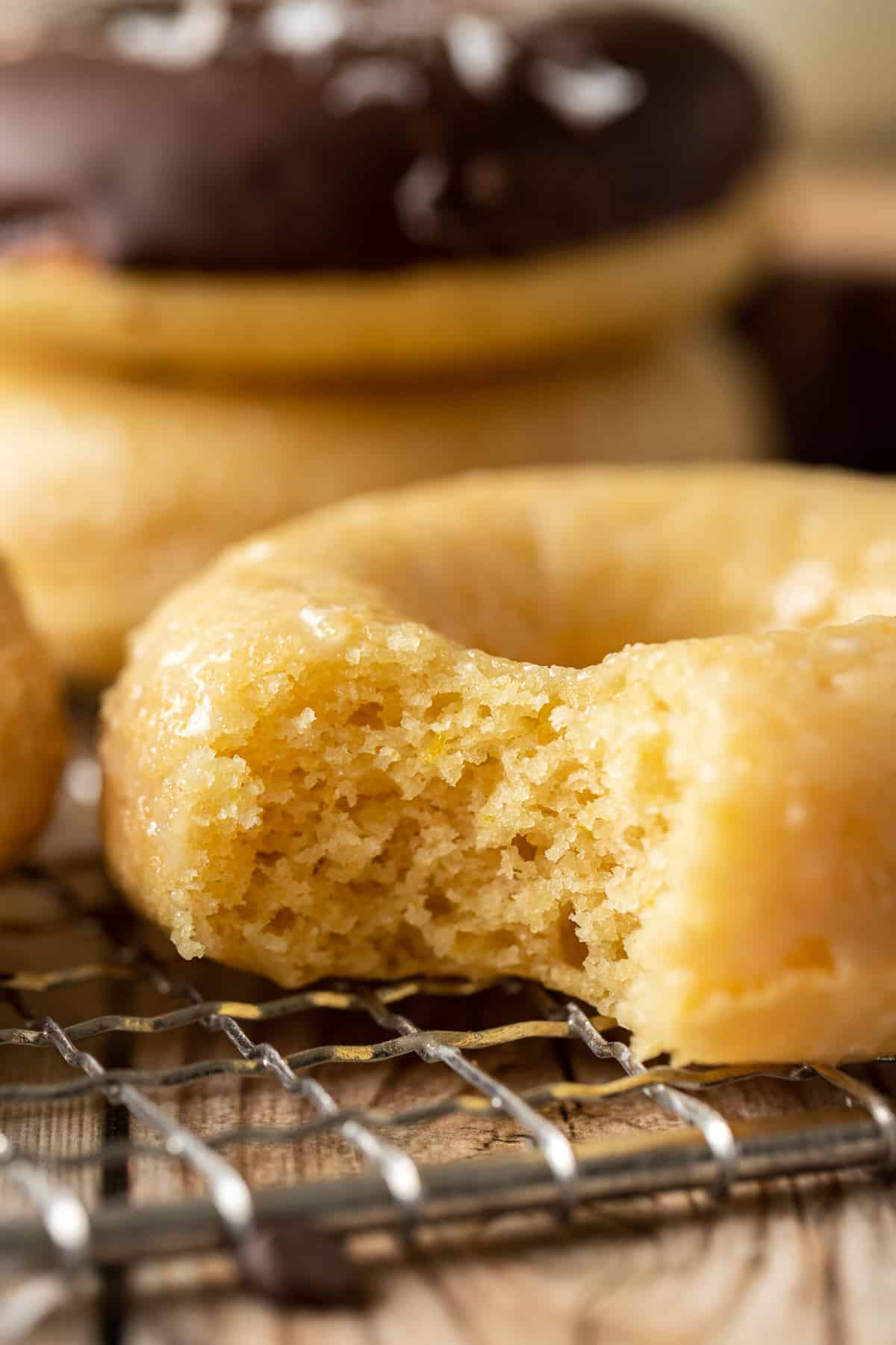 A glazed donut with a bite taken out on a wire cooling rack.