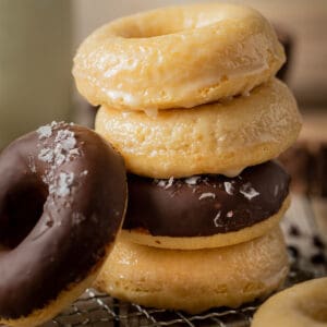 A stack of donuts half glazed and half chocolate on a wire cooling rack.