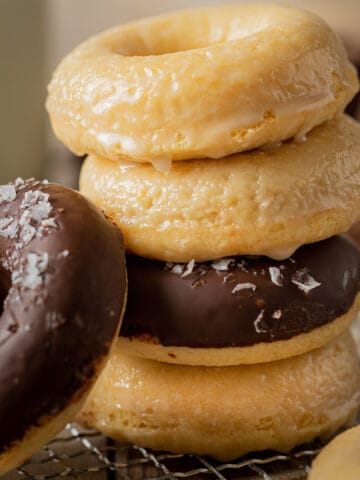 A stack of donuts half glazed and half chocolate on a wire cooling rack.