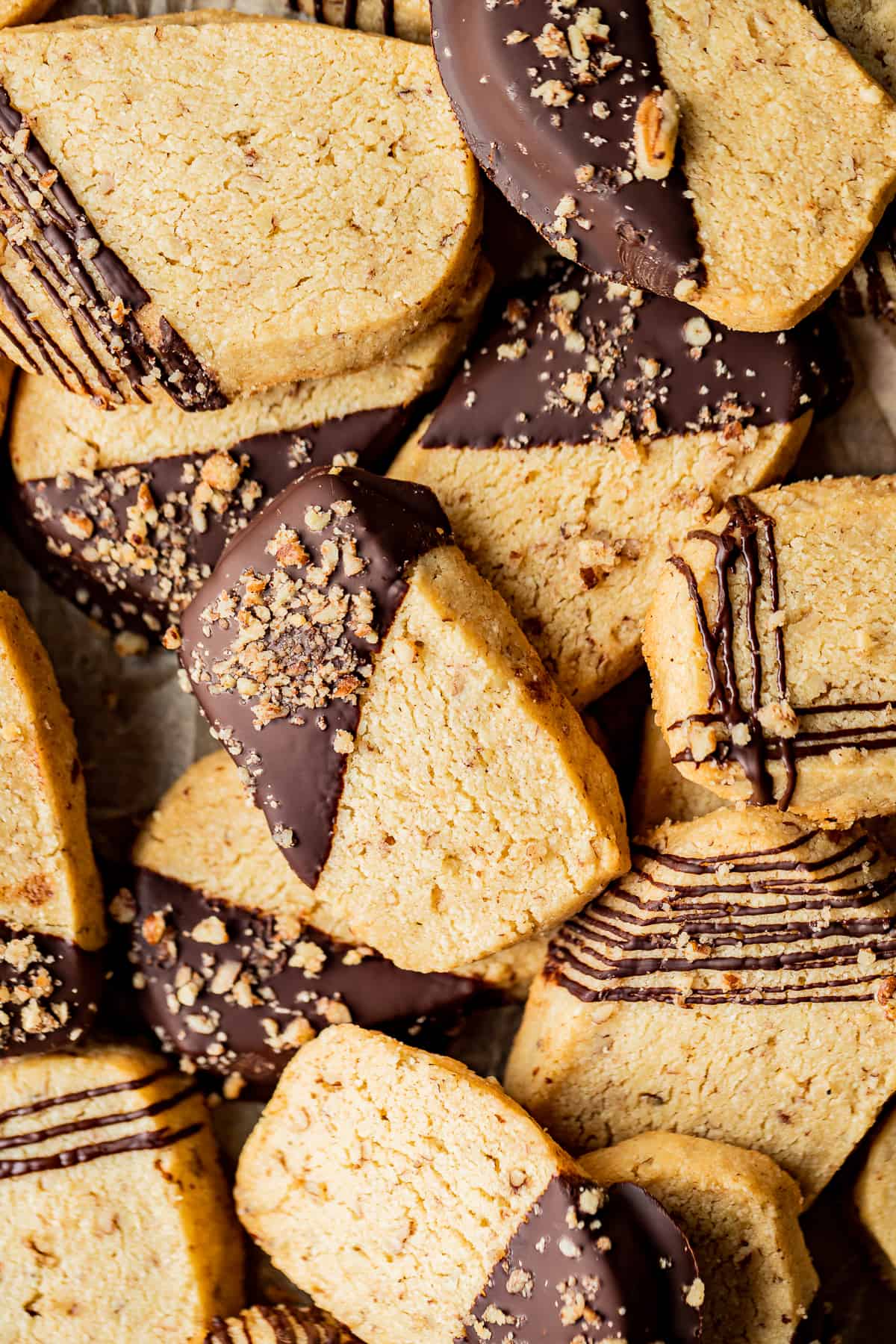 An overview shot of a pile of shortbread cookies dipped and drizzled in chocolate.