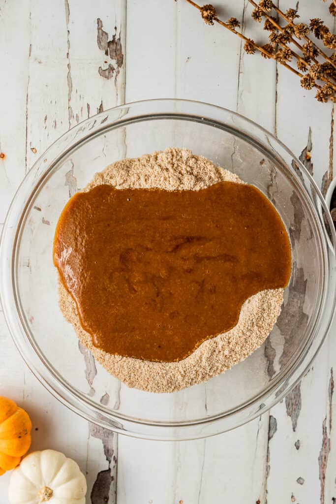 An overview shot of one bowl containing wet and dry ingredients being mixed for pumpkin muffins