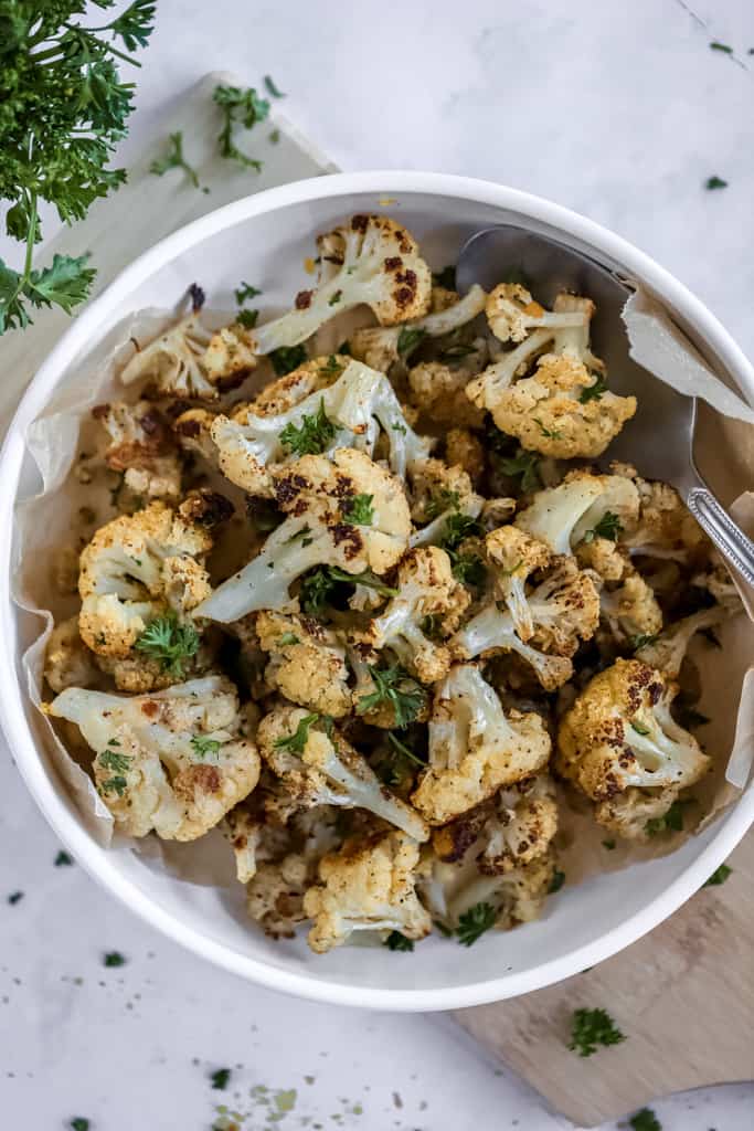 An overview shot of air fryer cauliflower with cumin on a grey background