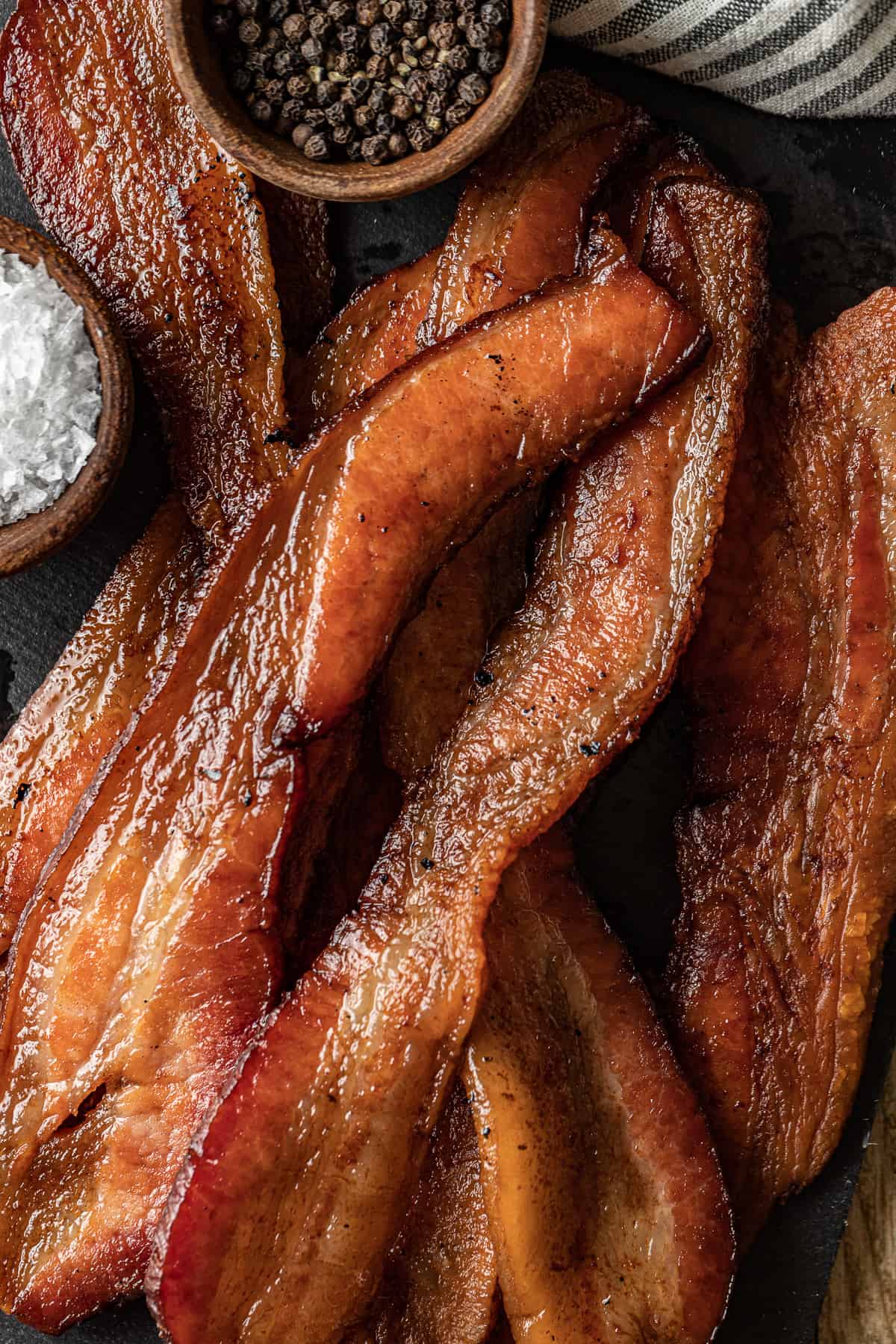 An overview shot of smoked bacon slices on a black background.