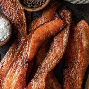 An overview shot of smoked bacon slices on a black background.