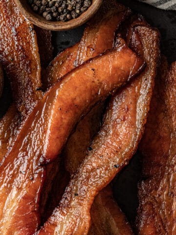 An overview shot of smoked bacon slices on a black background.