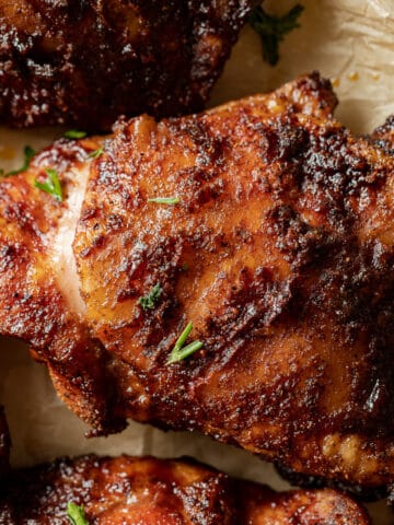 An overview shot of smoked chicken thighs plated and topped with parsley.