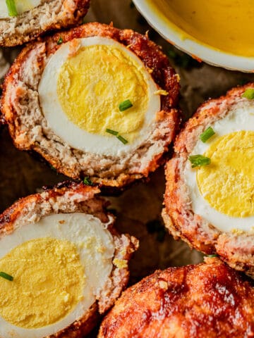 An overview shot of smoked keto scotch eggs cut in half and topped with green onions.