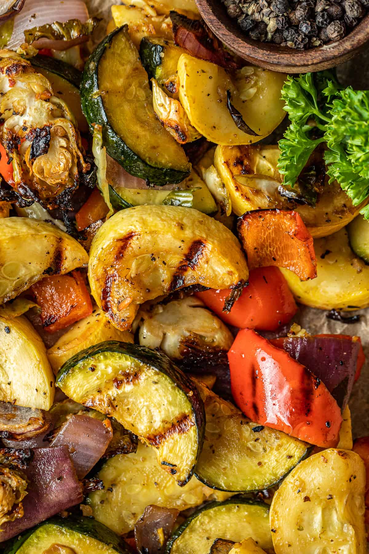A closeup overview shot of smoked vegetables on a baking dish lined with parchment paper.
