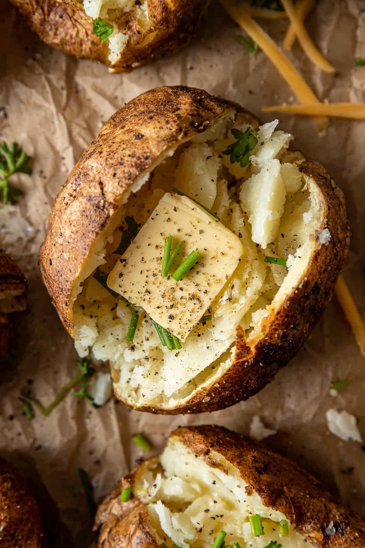 A smoked baked potato sliced open and topped with butter, salt, and pepper.