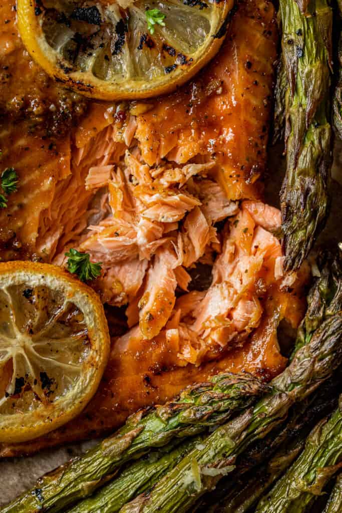 An overview shot showing flakey, cooked salmon topped with lemon wedges and parsley.