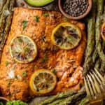 An overview shot of a whole salmon fillet topped with lemon and served with roasted asparagus.