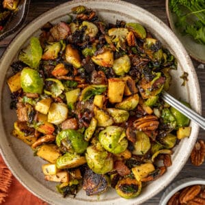 An overview shot of a bowl of brussel sprouts with apples and pecans topped with balsamic glaze.