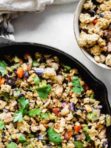 A pan of ground turkey and veggie next to a bowl full of turkey and veggies on a grey background